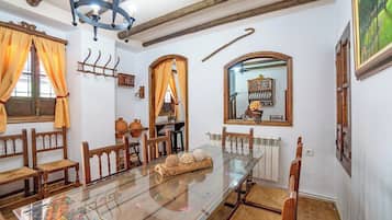 Comedor con mesa de vidrio, sillas de madera, un radiador y un espejo en la pared.