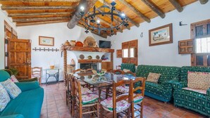 Un intérieur rustique avec une table à manger en bois, des chaises, un canapé vert et un lustre.