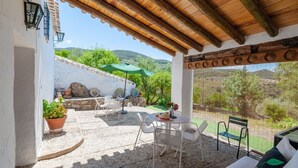Un patio couvert avec des sièges d’extérieur, une vue sur la campagne et un mur en pierre.