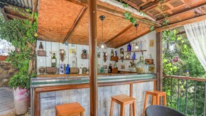 A rustic outdoor bar area with wooden beams, a glass counter, and various bottles and decorations.