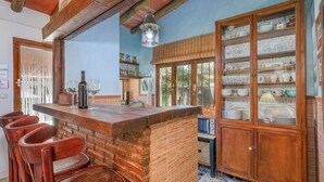 A kitchen with a wooden bar, brick wall, and a cabinet with glass doors.