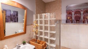 Ein Badezimmer mit einem Holzbadezimmer-Möbel, einer Glasdusche und einem Spiegel mit Blick auf die Stadt.