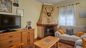 Una sala de estar con televisión, muebles de madera, una chimenea con astas y un sofá con cojines.