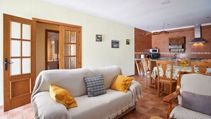 Una sala de estar acogedora con un sofá, un comedor con mesa y sillas, y una cocina con estufa y armarios.