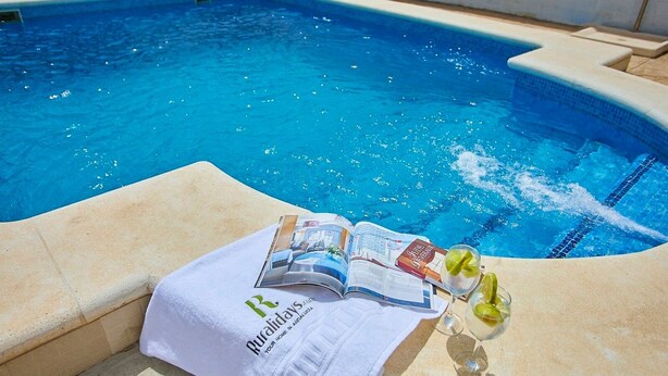 Zona de piscina con una toalla, una revista y un vaso de bebida con sabor a lima.
