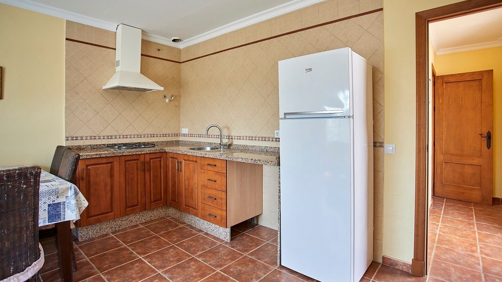 Une cuisine avec des meubles en bois, un réfrigérateur blanc et un pare-feu en carrelage.