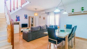 Una sala moderna con sofá, mesa de comedor, sillas y una escalera.