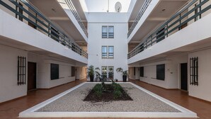 A spacious atrium with a central garden, high ceilings, and a modern architectural design. - Vilamoura Aldeia do Mar by Hopstays | Pool (Vilamoura)