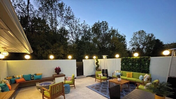 An outdoor patio with seating, a fire pit, and ambient lighting.