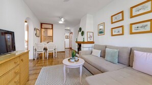 Un salon comprenant un canapé, un téléviseur, une table à manger, des chaises et des œuvres d’art accrochées aux murs.