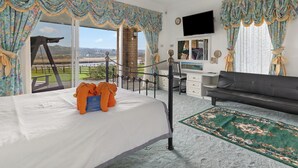 Una camera da letto con un letto, una scrivania, una sedia, un divano e vista sull'esterno.
