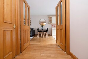 Un pasillo con puertas de madera que dan a un comedor con mesa y sillas.