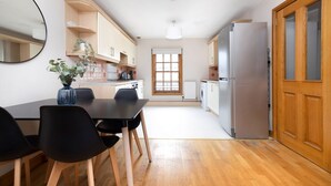 A modern kitchen with a dining table, chairs, a refrigerator, and a window. - Bright and Cosy Flat near The Scottish Gallery (Edinburgh)