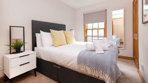 A bedroom with a bed, bedside table, and a window with a view. - Bright and Cosy Flat near The Scottish Gallery (Edinburgh)