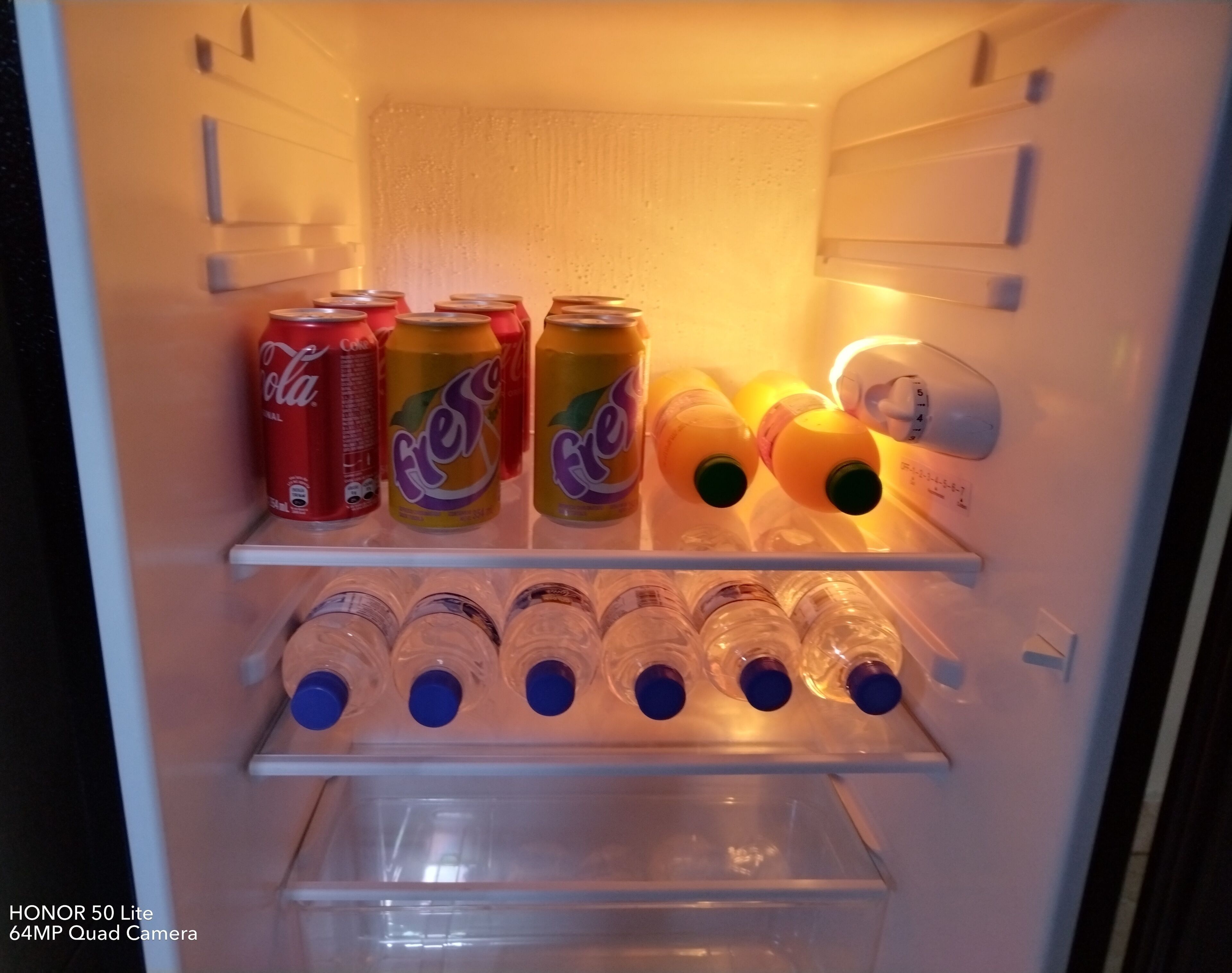 A refrigerator with shelves containing various beverages, including cans and bottles.