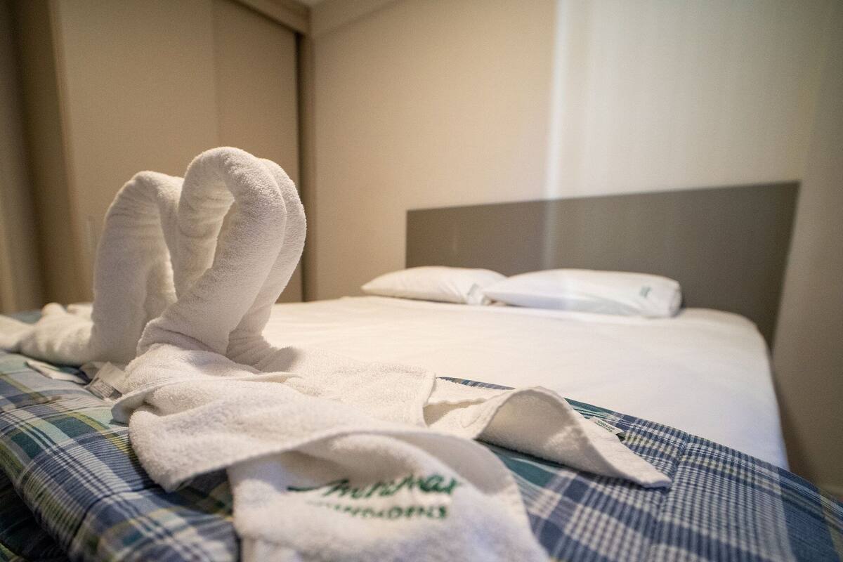 Ett hotellrum med en säng, en kudde och en handduk på sängen.