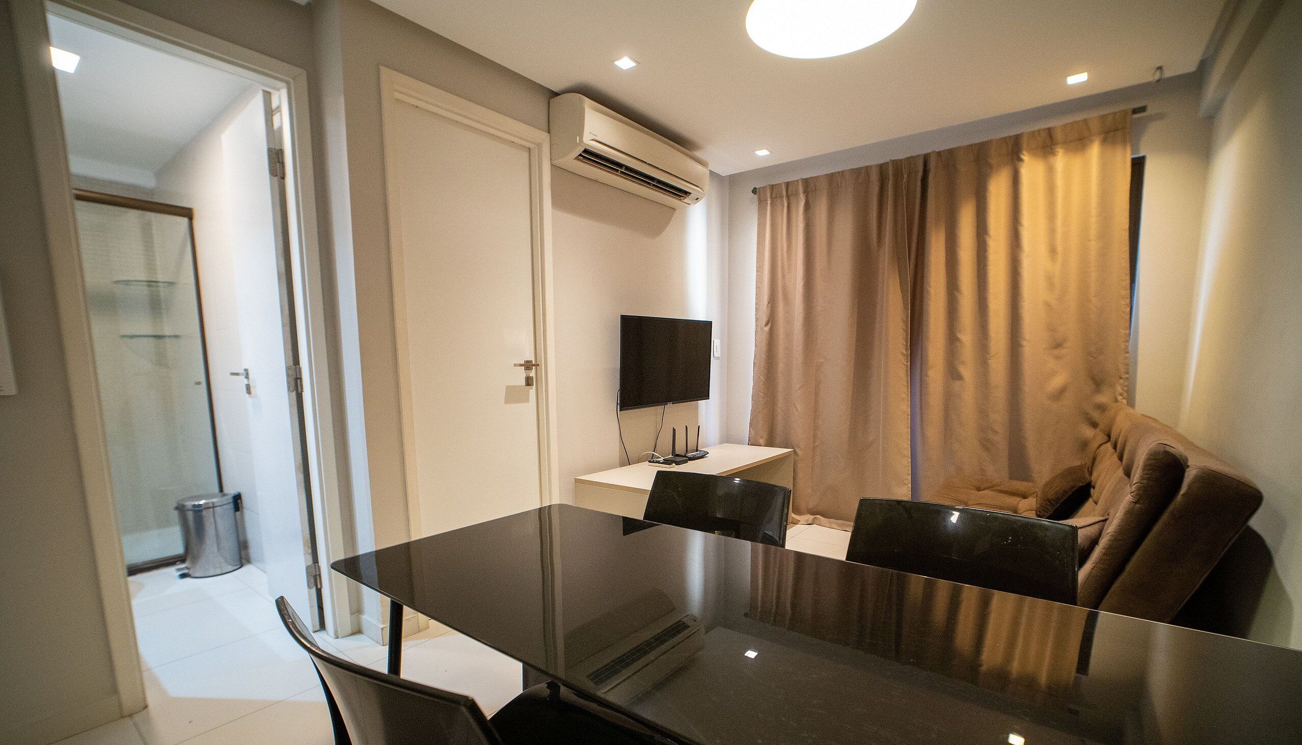 Una sala moderna con una mesa de comedor de vidrio, un televisor de pantalla plana y un sofá.