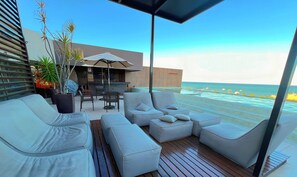 A deck with outdoor seating, a bar area, and a view of the ocean. - Holanda's Prime Residence (João Pessoa)