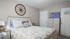 Una camera da letto con un letto, un comodino, una cassettiera, una televisione e una porta.