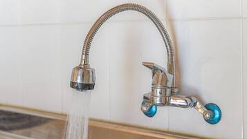 A bathroom with a chrome faucet and a flexible hose.