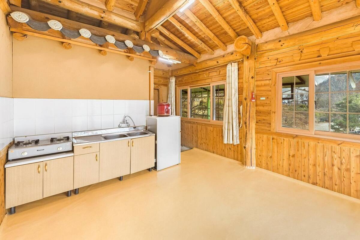Eine Küchenzeile im rustikalen Blockhausstil mit Herd, Spüle und Kühlschrank.