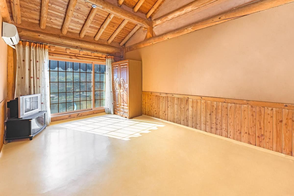 Ein Zimmer mit Holzboden, einer Schiebeglasdoor und einem Fernseher auf einem Standfuß.
