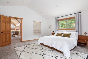 Una camera da letto con un letto grande, una testiera in legno, una finestra con tende e vista sull'esterno.