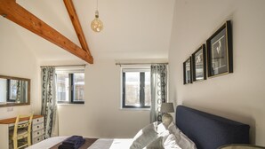 A bedroom with a bed, a desk, a chair, and a window. - The Stables (Lyme Regis)