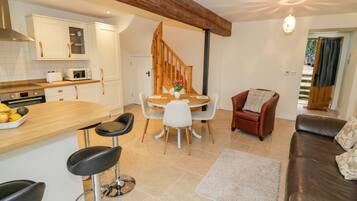A modern kitchen with white cabinets, a wooden dining table, and a staircase leading to another level.