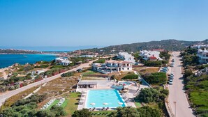Un complejo turístico frente al mar, con una amplia piscina, villas y vistas al océano.