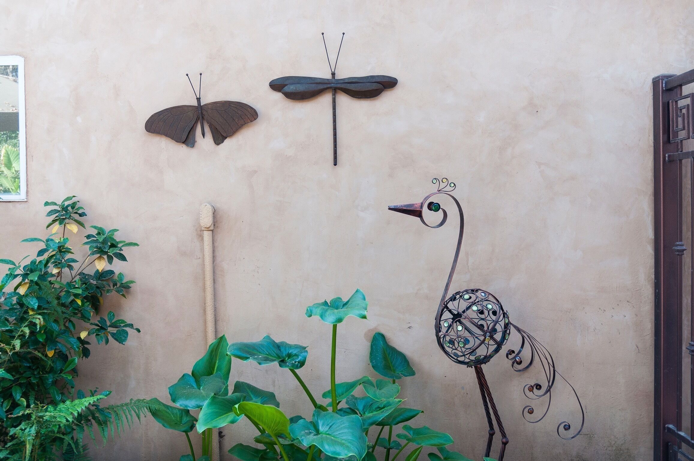 Un mur orné d’une sculpture représentant un papillon, une libellule et un oiseau.