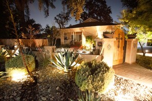 Ein Haus mit Veranda, einem verschlossenen Eingangsbereich und einem gut beleuchteten Garten mit verschiedenen Pflanzen.
