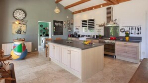 A spacious kitchen with a large island, wooden beams, and modern appliances. - Villa Merusellu (Sisco)