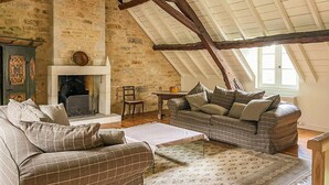 A cozy attic room with a fireplace, two plaid sofas, a patterned rug, and exposed wooden beams. - Gorgeous home in Sarrazac (Sarrazac)