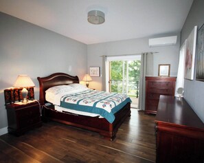 Relax in this serene space with a large bed, two nightstands, and a dresser, plus a window with a view of the surrounding greenery.