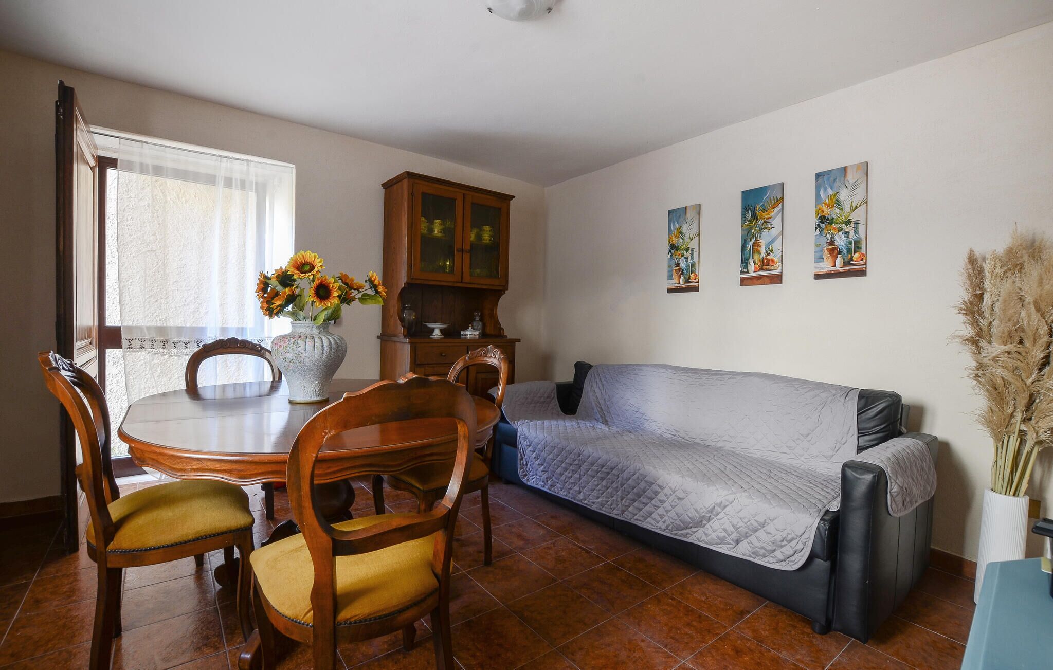 Un comedor con una mesa y sillas de madera, un armario y un sofá.