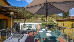 An outdoor patio with a table set for dining, surrounded by chairs and a large umbrella. - 2 bedroom lovely home in Valpromaro (Valpromaro)