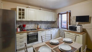 A compact kitchen with white cabinets, a built-in oven, a microwave, and a dining table set for four. - 2 bedroom lovely home in Valpromaro (Valpromaro)