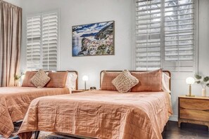 A hotel room with two beds, a painting of a coastal scene, and a view of the sea through large windows. - LUX 8BR/4BA Villa w/Heated Pool+Spa, 5min to Strip (Las Vegas)