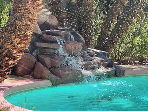 A pool with a waterfall feature surrounded by rocks and foliage. - LUX 8BR/4BA Villa w/Heated Pool+Spa, 5min to Strip (Las Vegas)