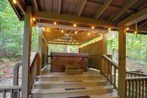 A wooden deck with a hot tub, steps leading to a covered area, and string lights. - 'TreeTop Retreat' Mentone Escape w/ Hot Tub (Mentone)