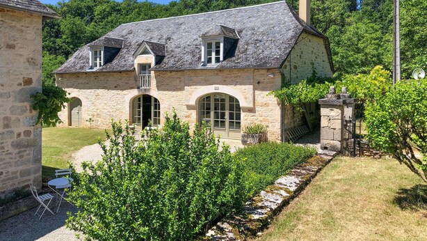 A stone house with a sloped roof, two arched windows, and a small garden area with a gravel path. - Nice home in Sarrazac (Sarrazac)
