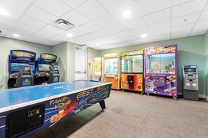 Ein Billardtisch mit 'Best Shot'-Werbung, zwei 'Rush'-Arcade-Automaten, ein 'Toy Chest'-Greifautomaten und ein Geldautomat.