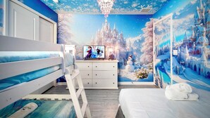 A bedroom with a bed, a dresser, and a TV displaying a movie scene. - New! Avatar Game Room & Harry Potter Fantasy World (Davenport)