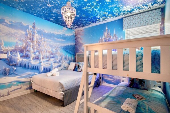 A child's bedroom with a bunk bed, a mural of a snowy castle, and a chandelier.