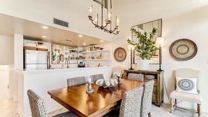 A dining area with a wooden table, woven chairs, and a chandelier.