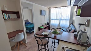 A compact hotel room with a bed, a desk, a dining area, and a kitchenette. - Beautiful apartment, comfortable with excellent location (Santiago)