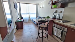A compact kitchen with a dining area, a small bar stool, a sink, and a stove. - Beautiful apartment, comfortable with excellent location (Santiago)