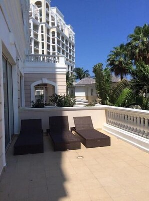 Enjoy the stunning view of the surrounding architecture from this hotel's balcony, featuring comfortable lounge chairs.