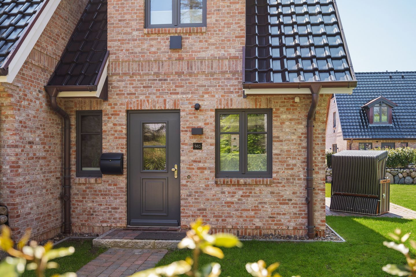 A brick house with a dark front door, a mailbox, and a small garden.